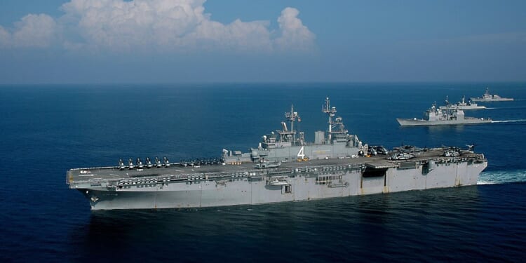 The USS Boxer, an amphibious assault ship, at sea on a sunny day.