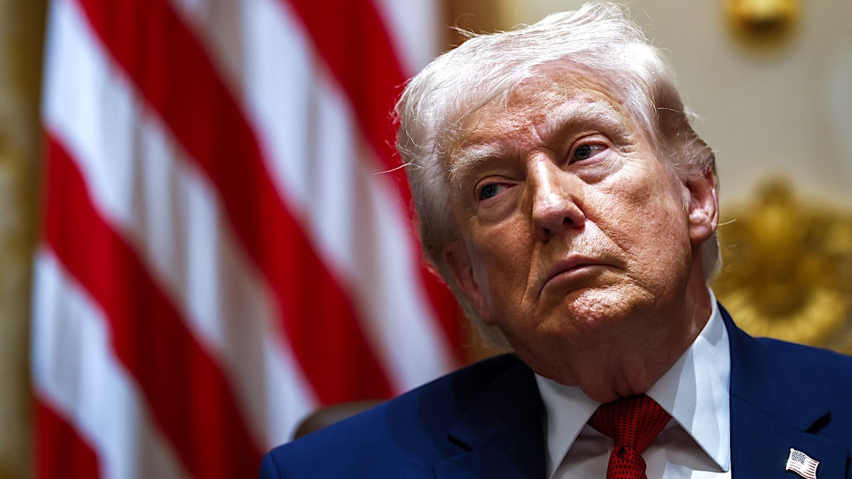 President Donald Trump sits in front of an American flag at a cabinet meeting
