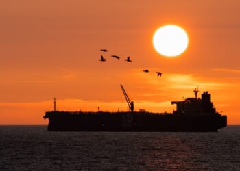 An oil tanker seen in shadow at dusk.