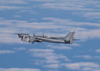 A Russian Tu-95 bomber aircraft in flight against a cloudy sky.