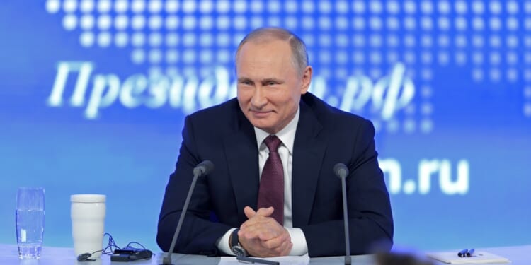 Russian President Vladimir Putin smiling at a press conference.