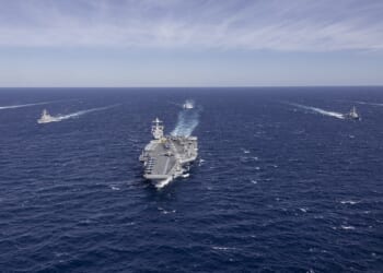 The USS Gerald Ford leading a group of ships on the ocean.