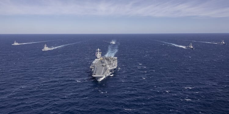The USS Gerald Ford leading a group of ships on the ocean.