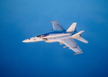 An F/A-18 Super Hornet in flight against a blue backdrop.