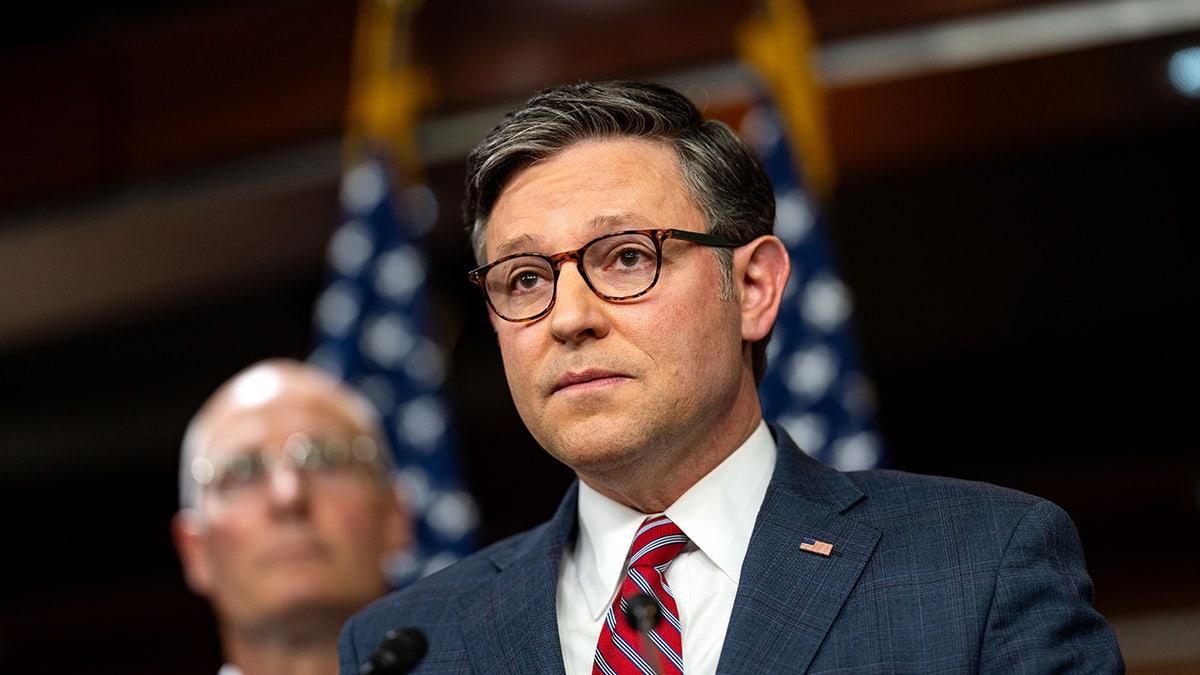 Mike Johnson looks at reporters during a press conference.