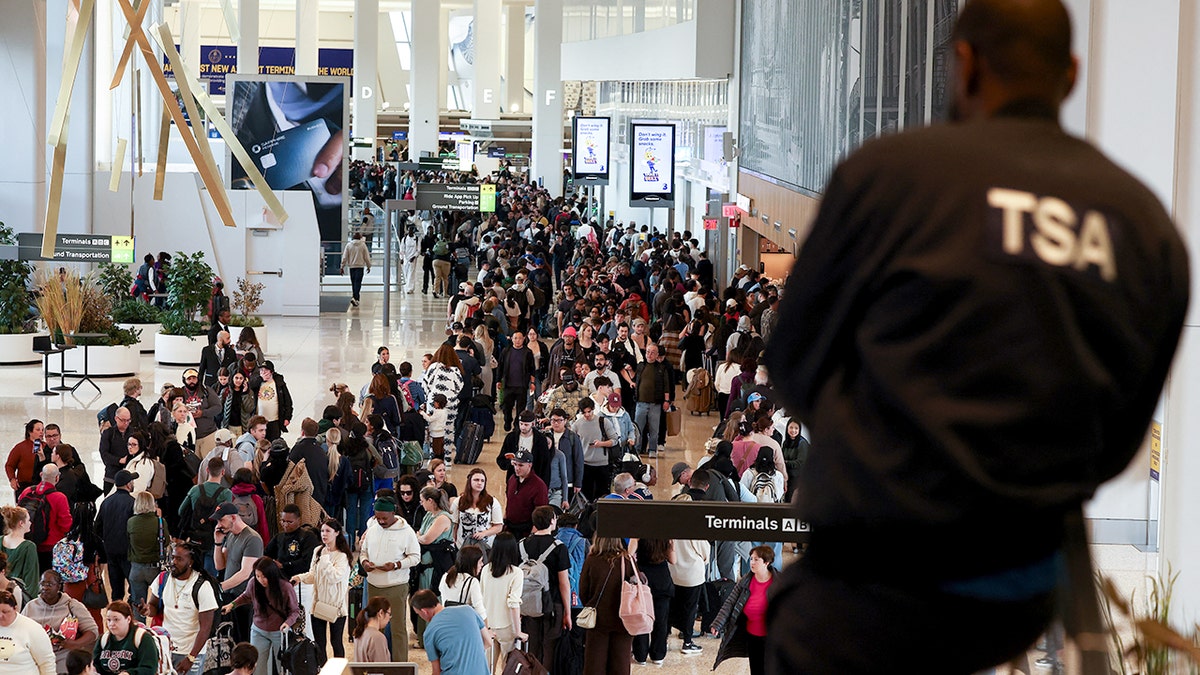 TSA agent watching passengers queue at LaGuardia airport security checkpoint