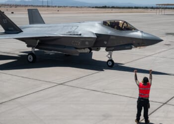 An aircraft marshal guides an F-35 fighter jet on the tarmac.