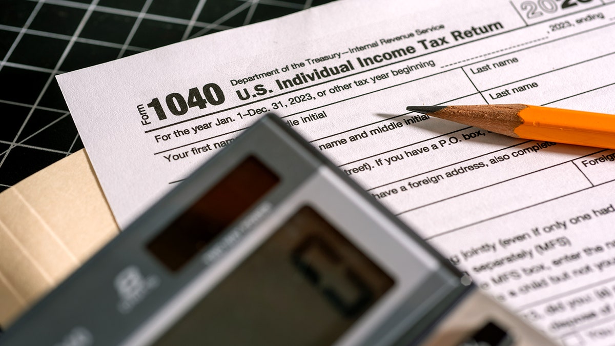 A 1040 tax form is covered by a pencil and a calculator.