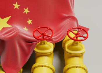A Chinese flag drapes over industrial gas pipelines.