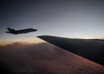 An F-35 flying next to a KC-135 in darkness.