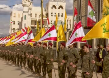 A procession of Hezbollah soldiers carrying flags.