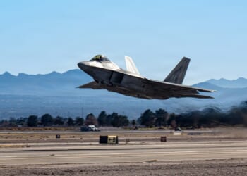 An F-22 Raptor taking off from an airfield in the desert.