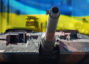 A Leopard tank in front of a Ukrainian flag.