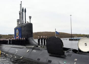 Sailors stand on a submarine during its commissioning ceremony.