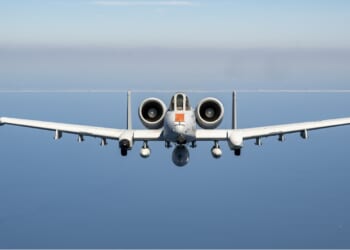 An A-10 Warthog in flight over a blue body of water.