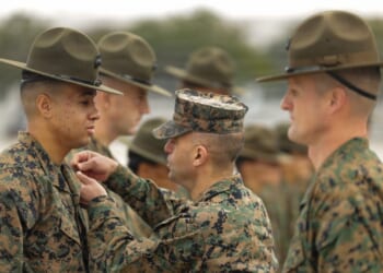 A Marine instructor pins an insignia on a recruit.