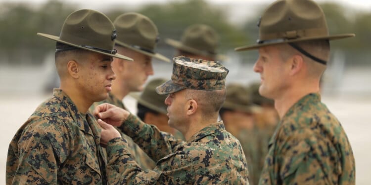 A Marine instructor pins an insignia on a recruit.