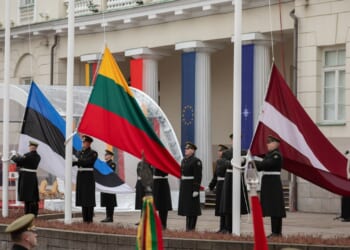 The three flags of the Baltic states being raised from three flagpoles.