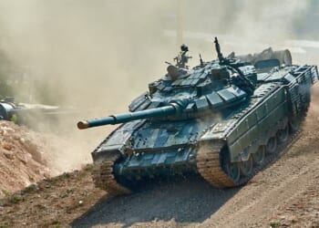 A Russian T-90 tank driving through dirt.