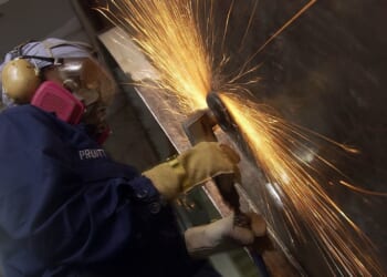 A Navy sailor using a power tool.
