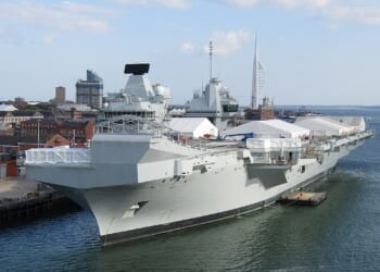 The HMS Prince of Wales in port, with tents pitched on its deck.