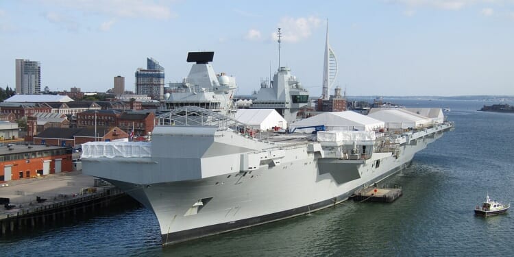 The HMS Prince of Wales in port, with tents pitched on its deck.