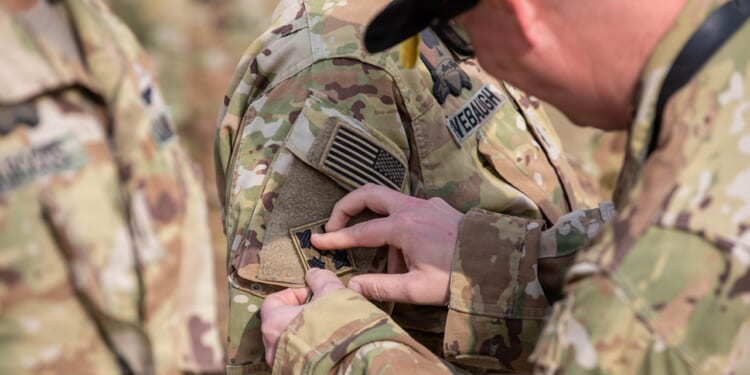 A soldier being given a combat patch in the Army.