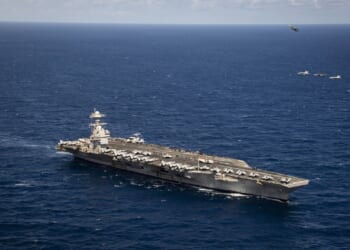 The USS Gerald R. Ford against a blue sea and a clear sky.