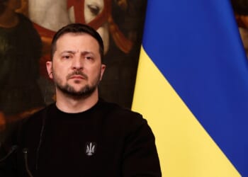 President Volodymyr Zelensky speaks in front of a Ukrainian flag.